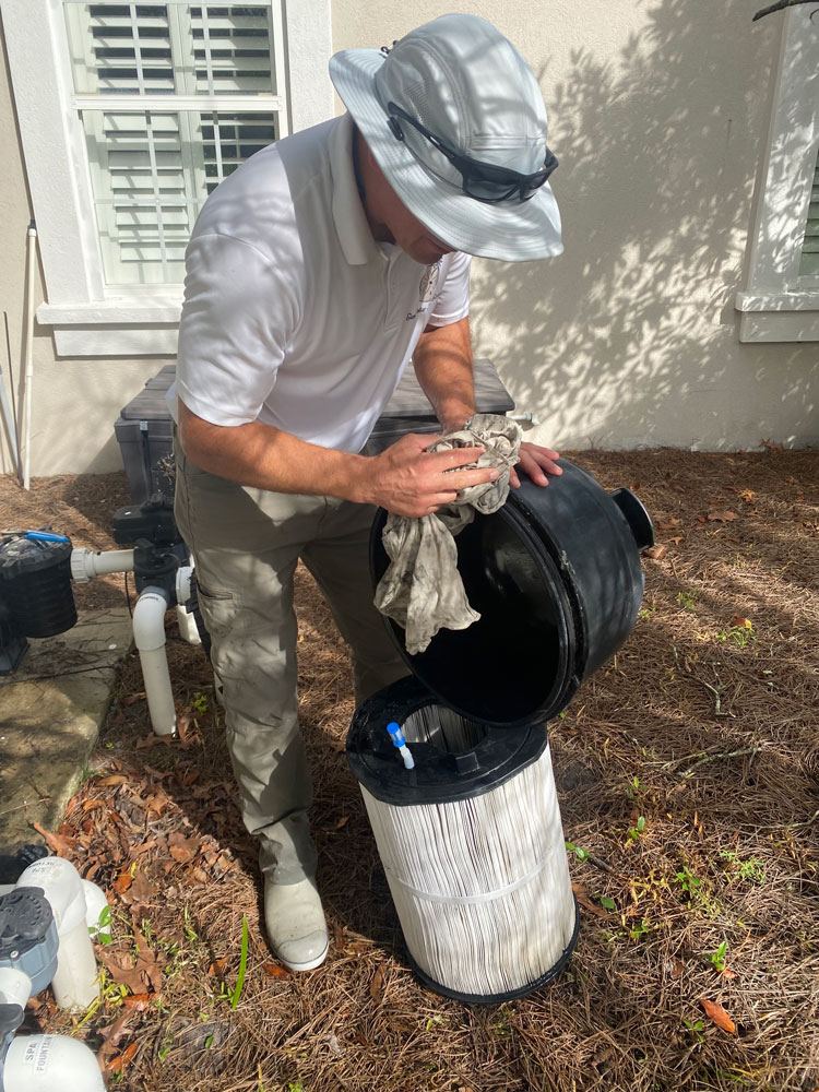 man cleaning pool filter